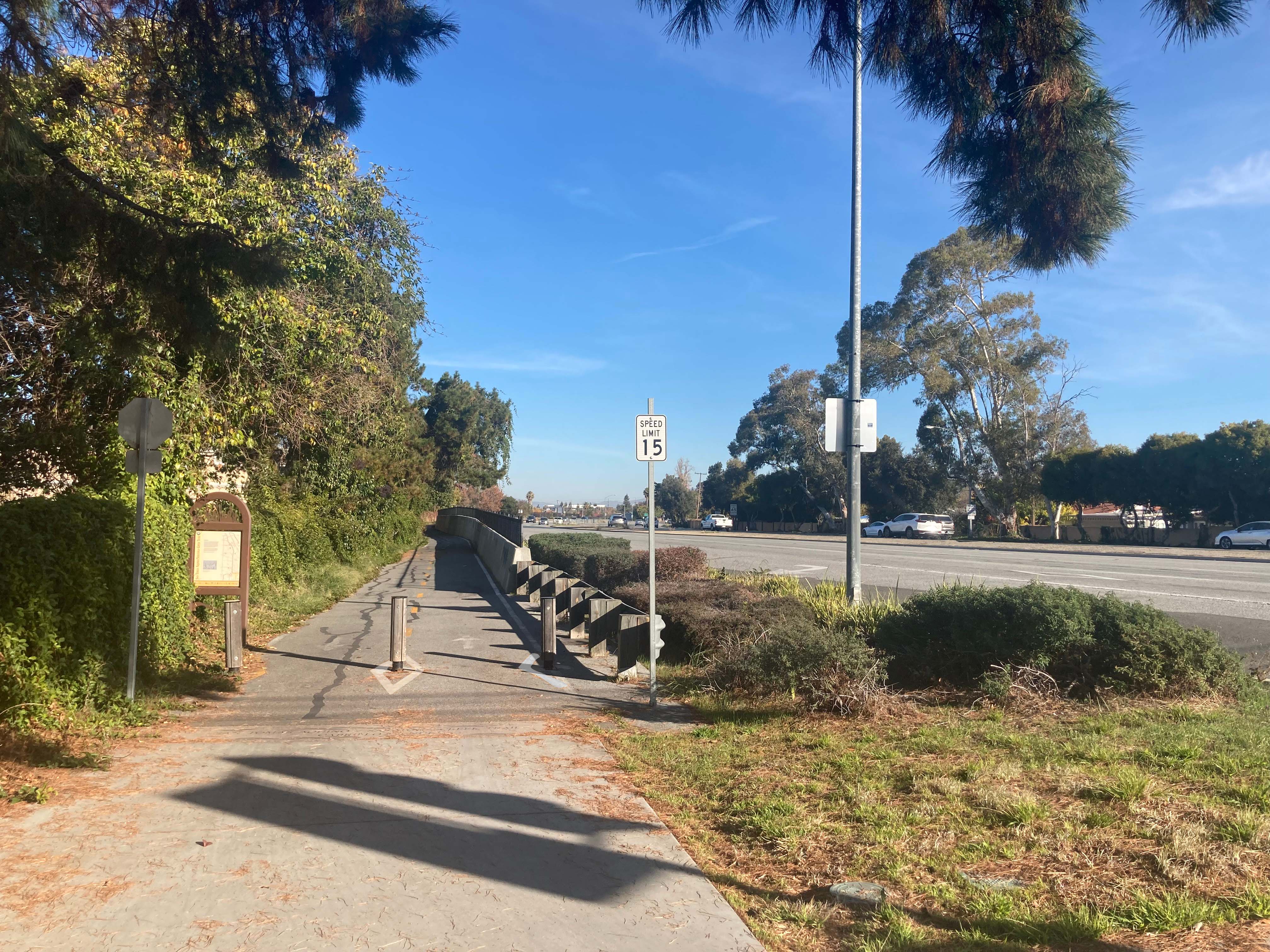 tree-lined road with a speed limit 15 sign between the road and pedestrian trail. Image Credit: FHWA